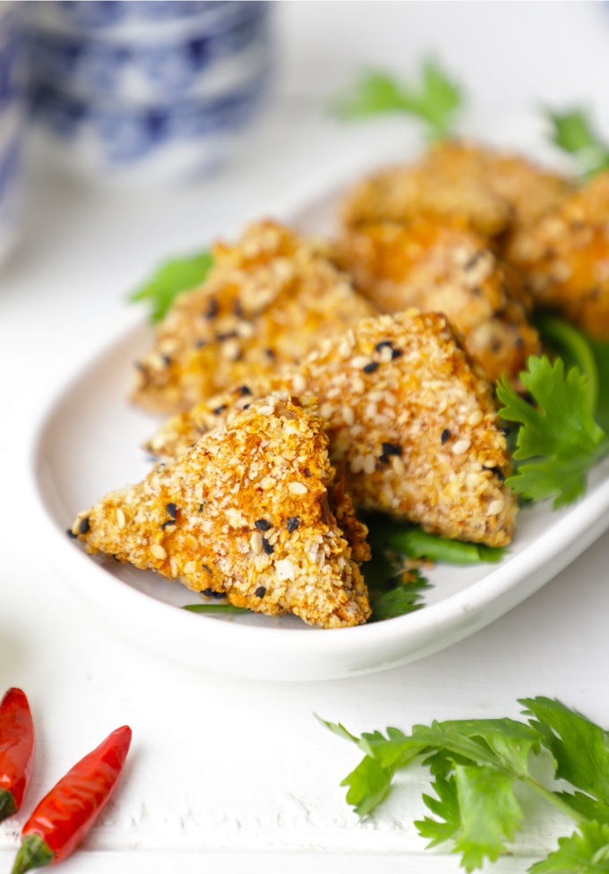 side shot of crispy tofu stacked on a white plate
