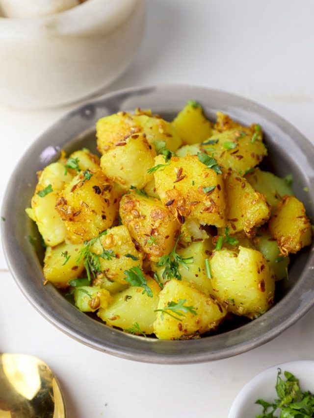 side close up shot of jeera aloo in a grey bowl