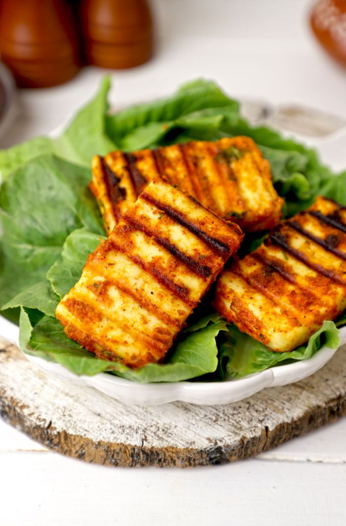 side shot of grilled paneer served on lettuce leaves