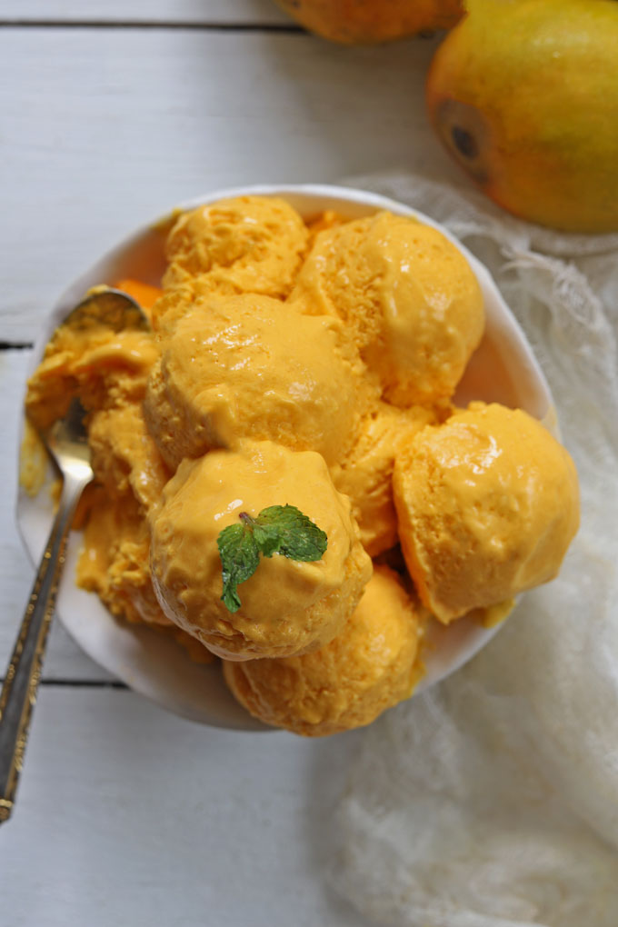 Aerial shot of mango ice cream in a white serving bowl with a spoon.