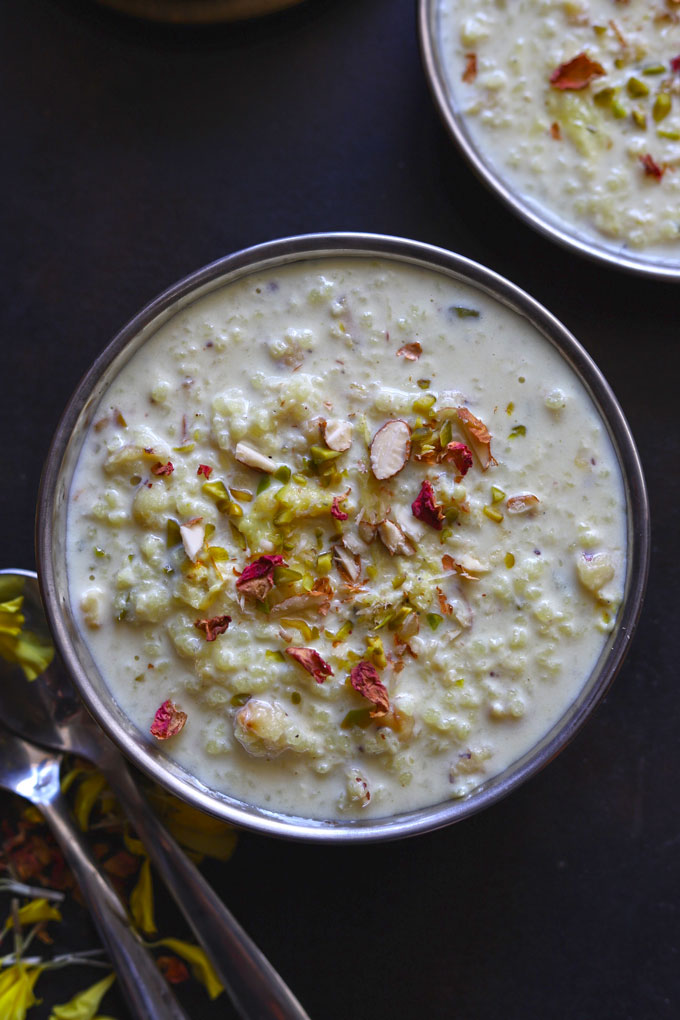 Aerial shot of Millet Kheer in a stainless steel bowl with spoons on a black background.